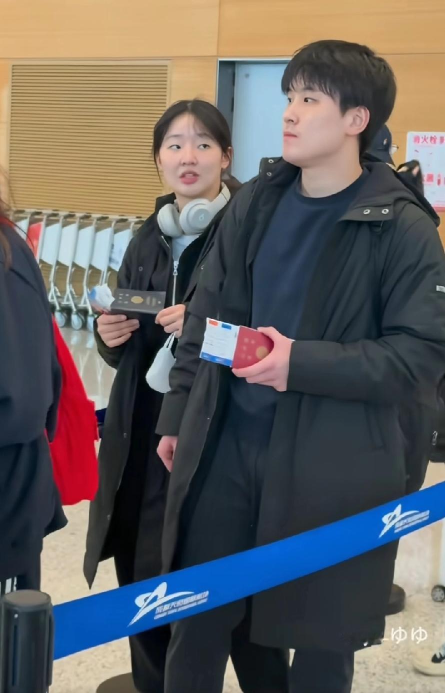 张本智和兄妹俩，在成都机场排队乘飞机，去香港参加比赛，二人穿着黑色长款羽绒服，日