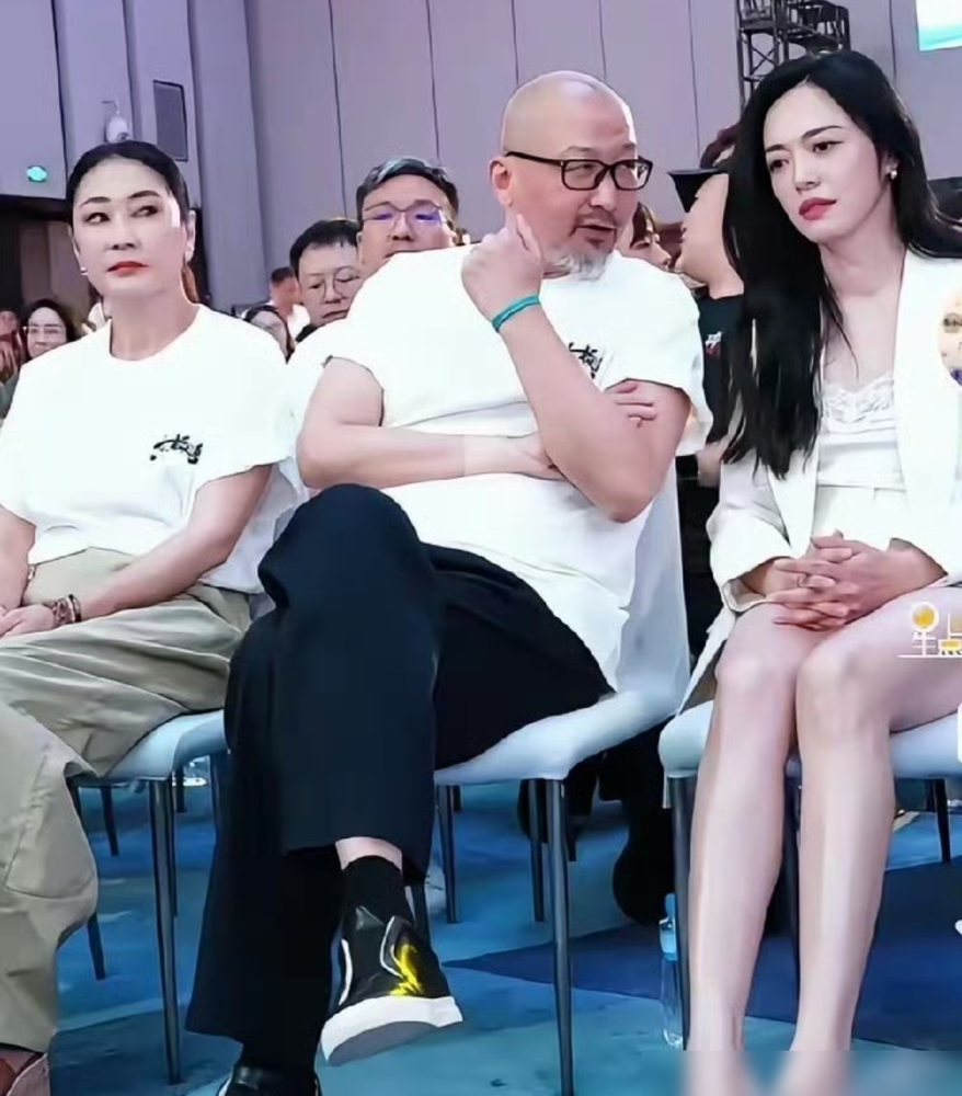 管虎左边坐着老婆梁静，右边紧挨着倪妮，聊得那叫一个热乎。梁静就那样侧着头，眼睛直勾勾盯着他俩，脸上看