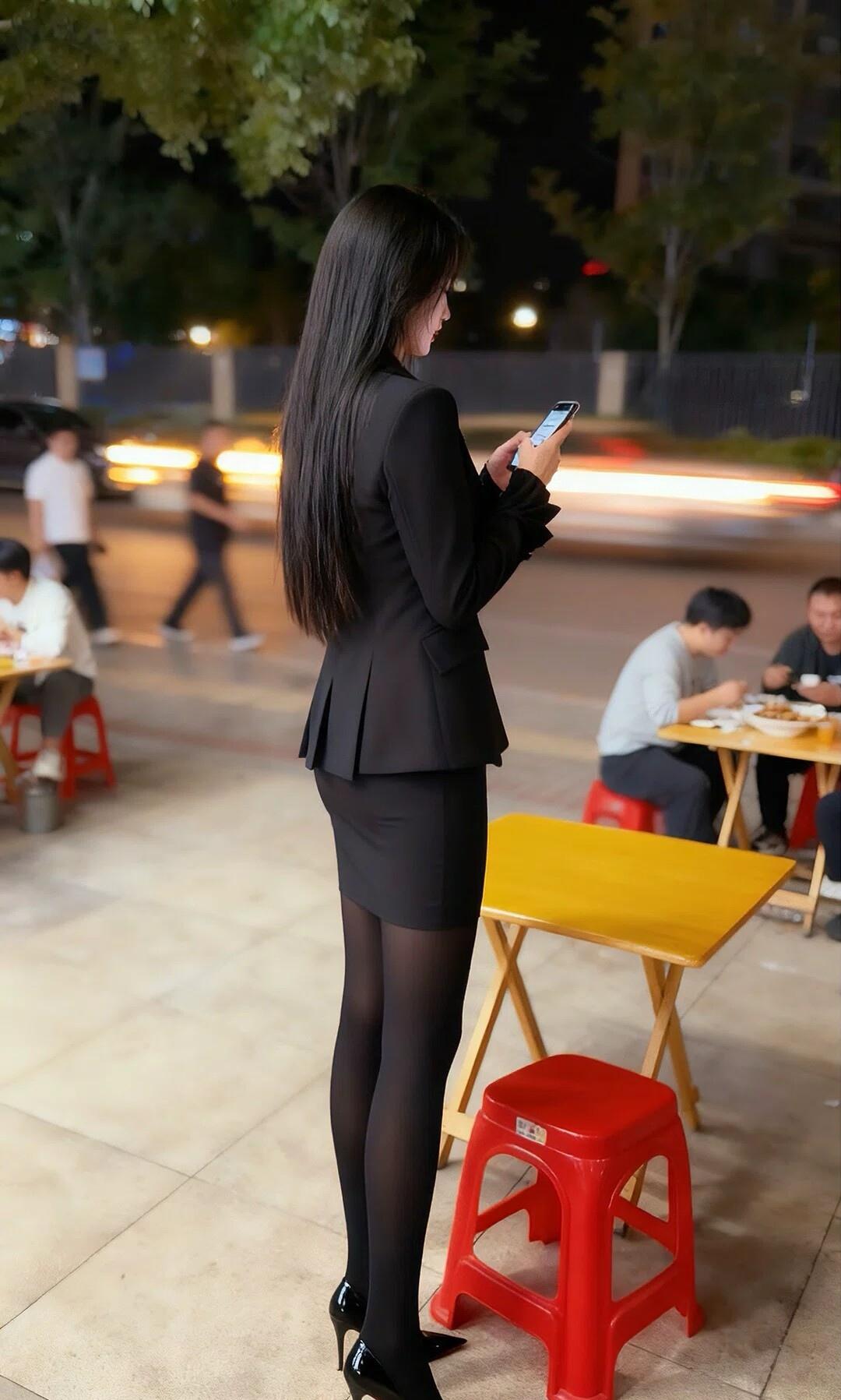 都市夜色下的优雅身影，手机里的世界与现实交织。