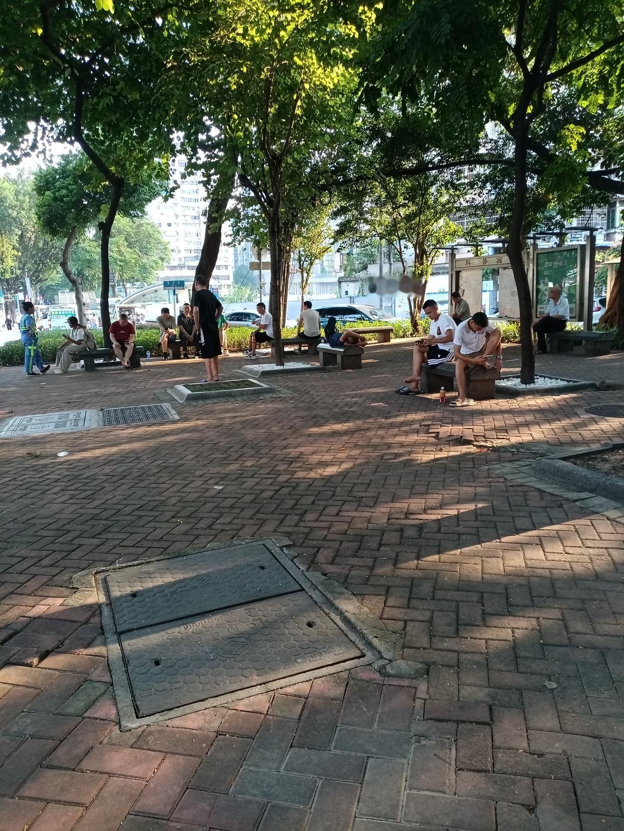 广州海珠区敦和路口小公园，好多人做在石凳子上面聊天玩手机。还有好多人睡在