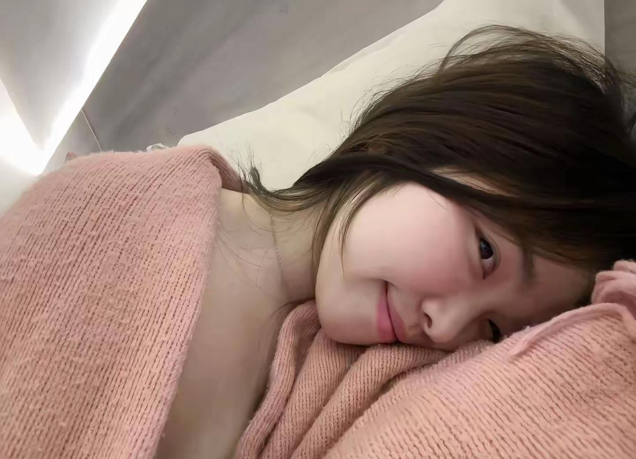 裹着软乎乎的粉毛衣赖在床上，半眯着眼笑的样子，像揣了一团棉花糖在怀里，慵懒又甜。
