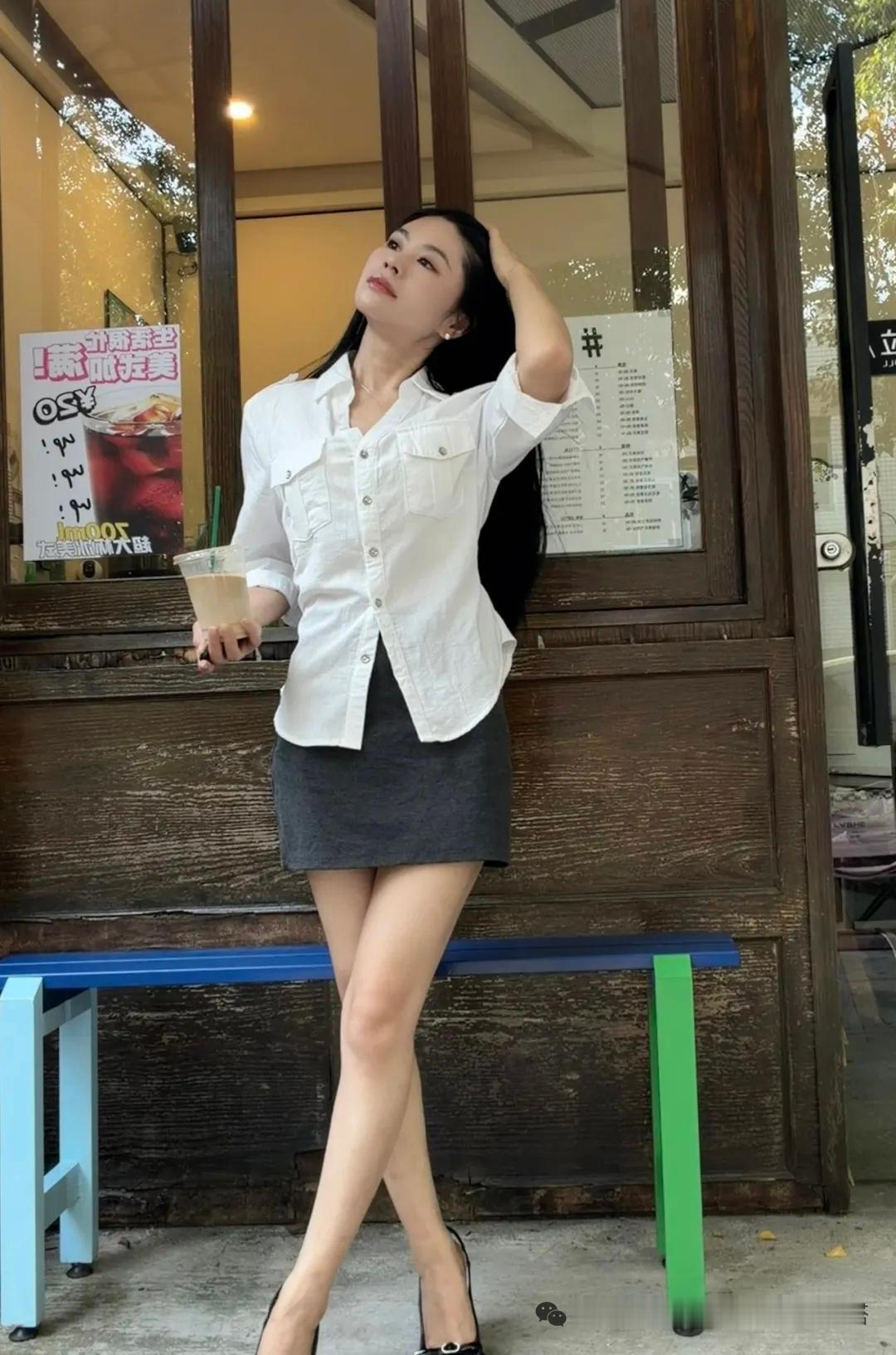 一个女孩靠在长椅上，喝着饮料。