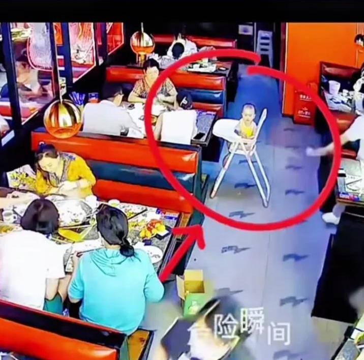 惊险！父母在餐厅吃饭时，把婴儿餐车放在过道中间，小小的孩子就坐在餐车上。不料，婴