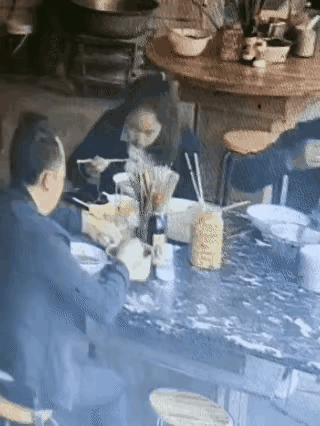 一位男子在饭店吃面，吃完了，男子没走，竟然把桌子上一大碗的辣椒油全部倒在了他自己