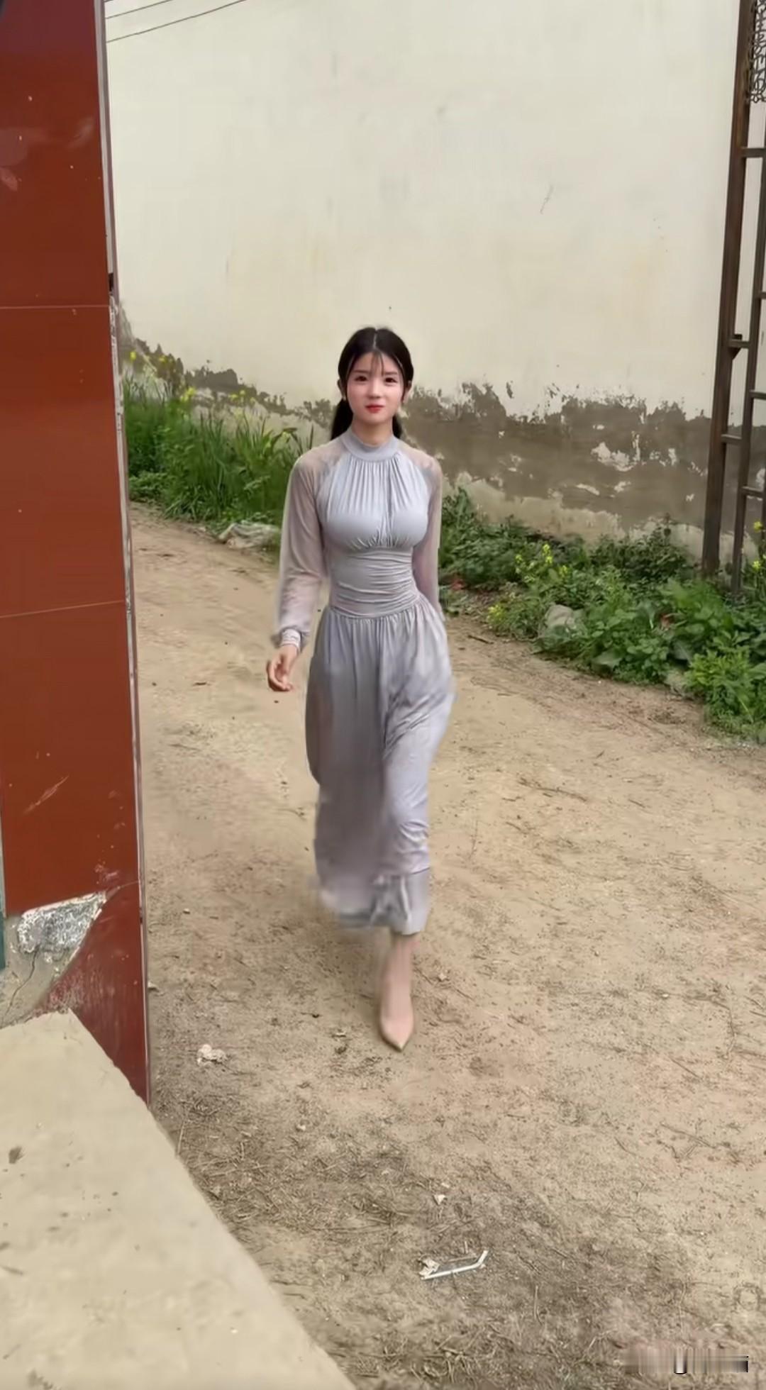 春日的乡村小路，风里裹着油菜花的淡香，还有泥土刚被晒过的软润气息。她一身浅灰色长