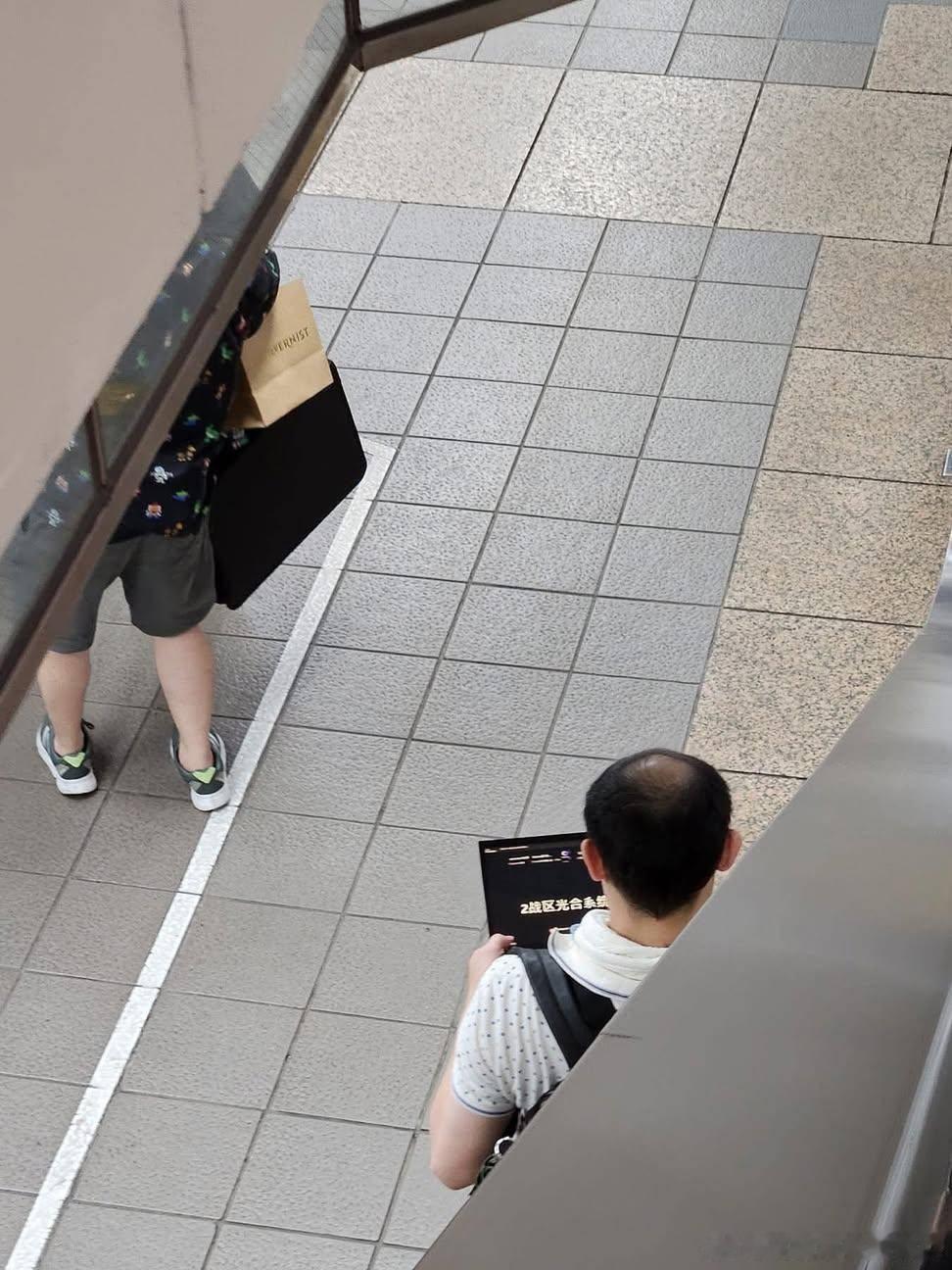 台北车站，一名手持笔记本电脑的人正在车站内行走。由于电脑屏幕上的内容引发关注，岛