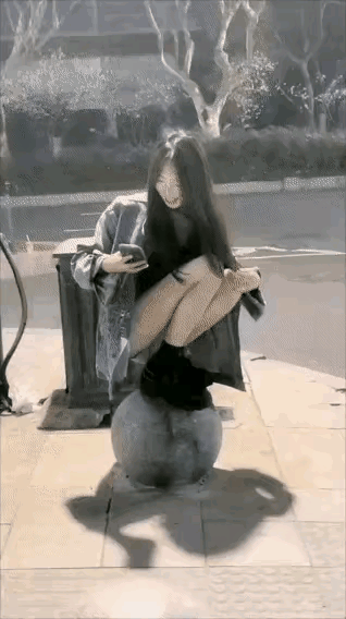 嘚瑟，自己作死的节奏！一名美女，脚穿皮鞋，先是蹲着在一个圆石上面看手机，然后站起