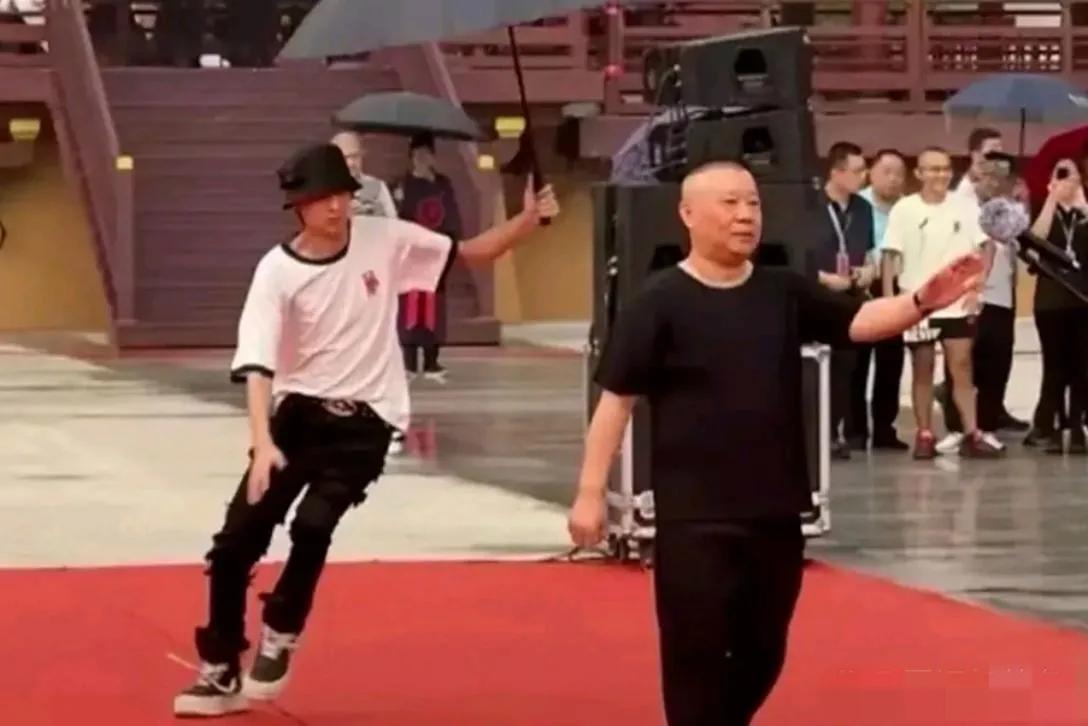 瞧，身材瘦弱的秦宵贤真会来事，真有眼力见哈，为给郭德纲打伞竟然差点儿滑倒！