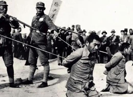 1946年8月，上海江湾刑场，16个汉奸排成一排等着吃枪子。其中一个人被五花大绑