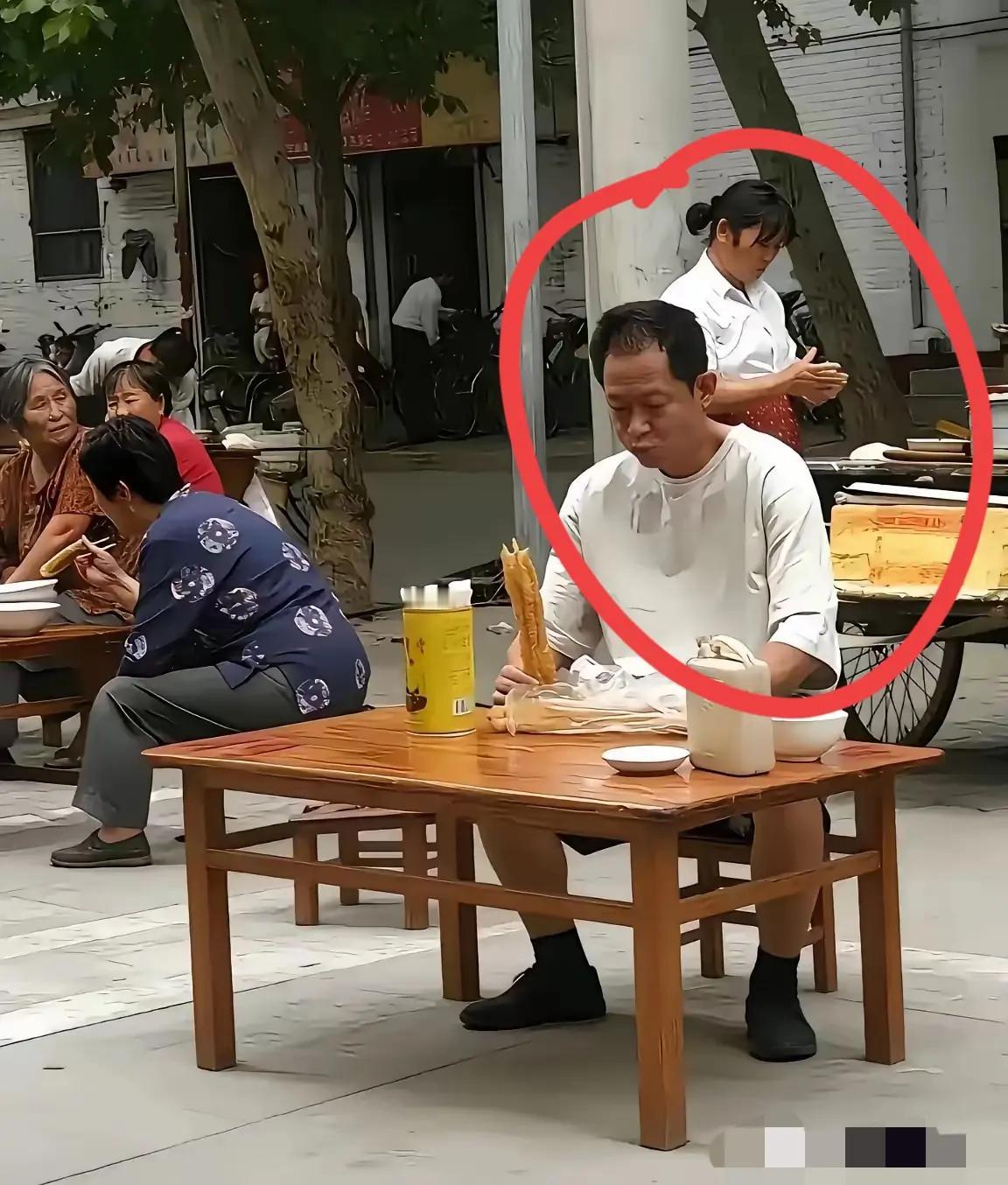 王志文坐在街头小摊吃油条，一身白T恤，眼神里透着从容与淡定。大明星也能这么接地气