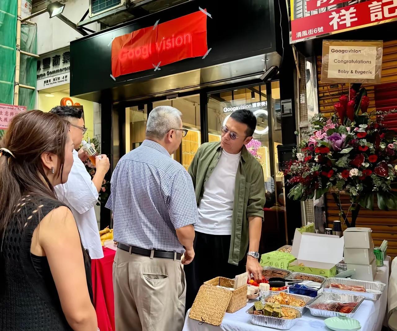 香港街头撞见苗侨伟戚美珍夫妇为眼镜铺开业站台，67岁的三哥穿休闲装依旧挺拔有型，