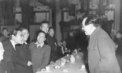 伟大领袖毛主席在坐谈会上与教育家雷洁琼互动，毛主席微笑着和在坐人士交谈，左二戴眼