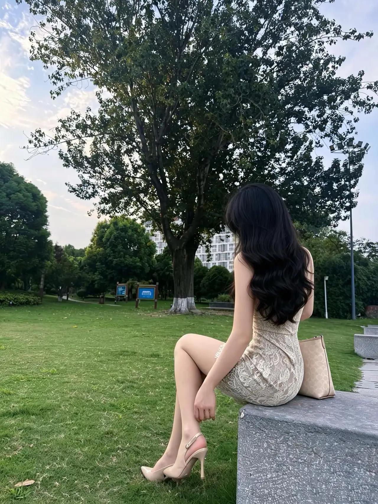 一位美女坐在公园的石凳上，享受悠闲时光！