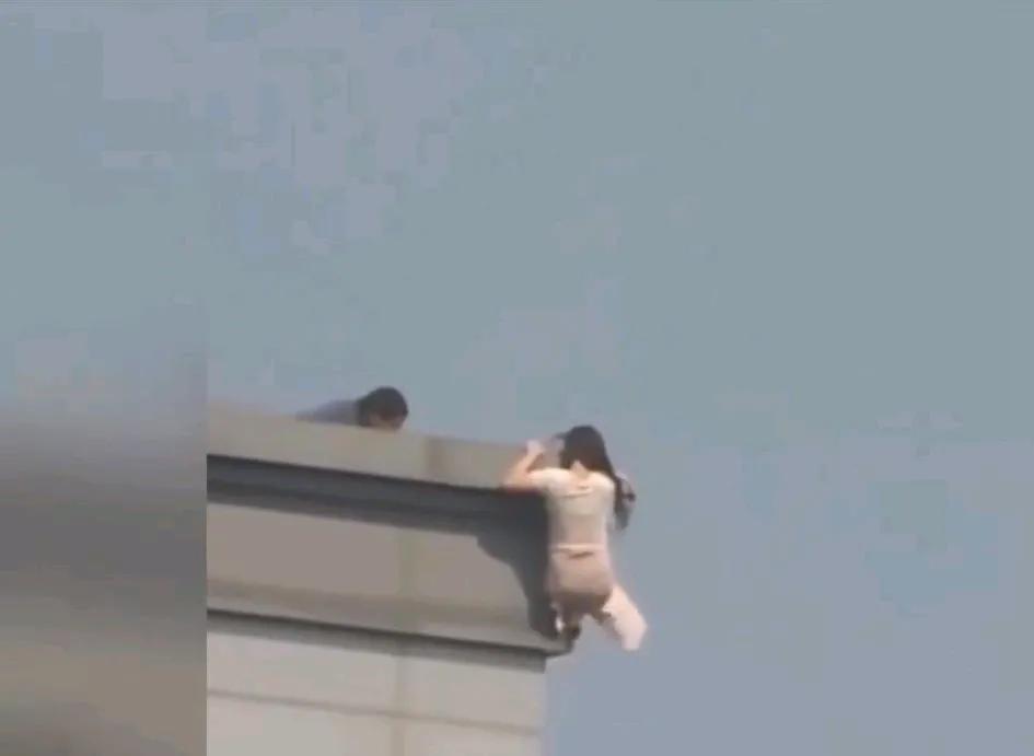 女子从20楼跳下，在千钧一发之际，男子瞬间拉住女子的手，另一只手抓住女子头发，真