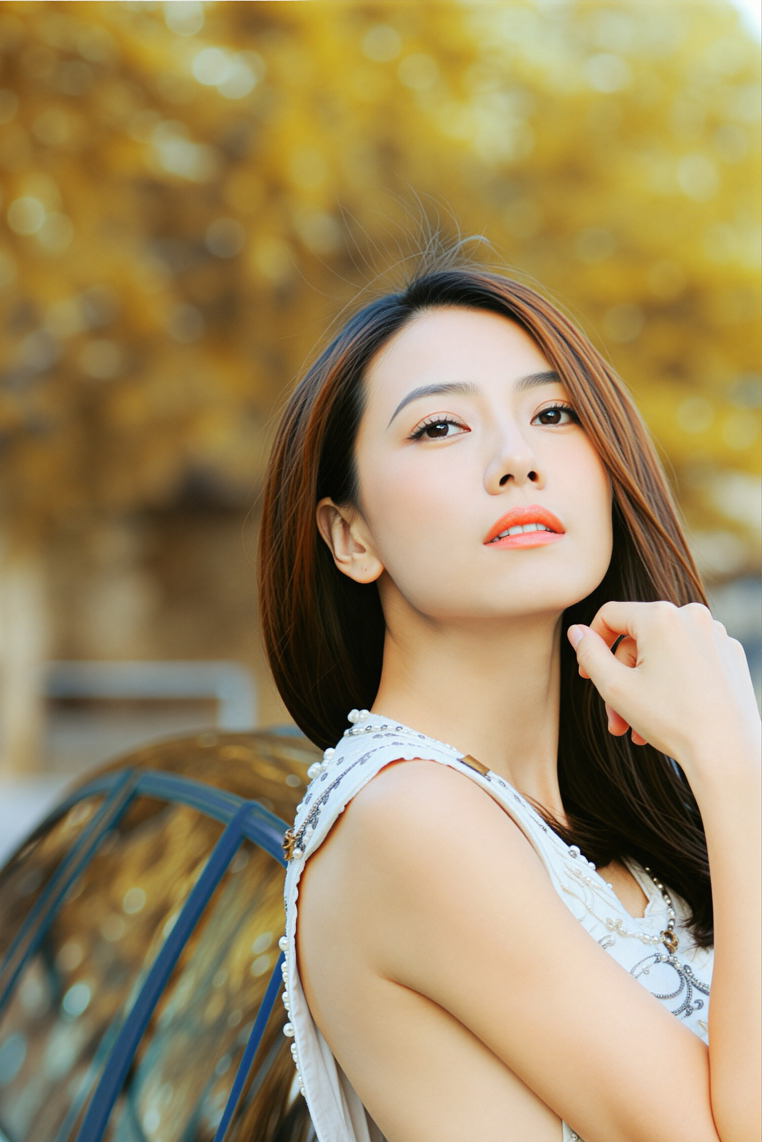 高圆圆暖黄秋光里，她长发垂落，眉眼清润又带着几分笃定，白裙衬得肩线舒展，指尖轻