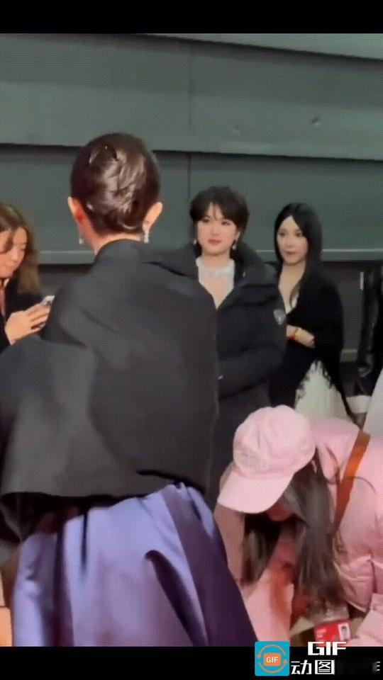 助理正在帮杨幂整理晚礼服下摆，身后走来了一群人，走在前面的是华为二公主姚安娜，二