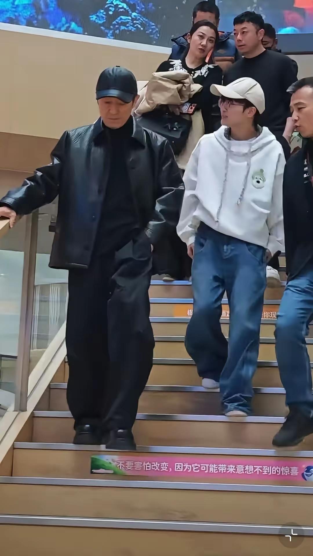 张艺谋，周深同框现身阿里大楼成焦点！镜头下的张艺谋身穿皮衣，头戴黑色棒球帽，下
