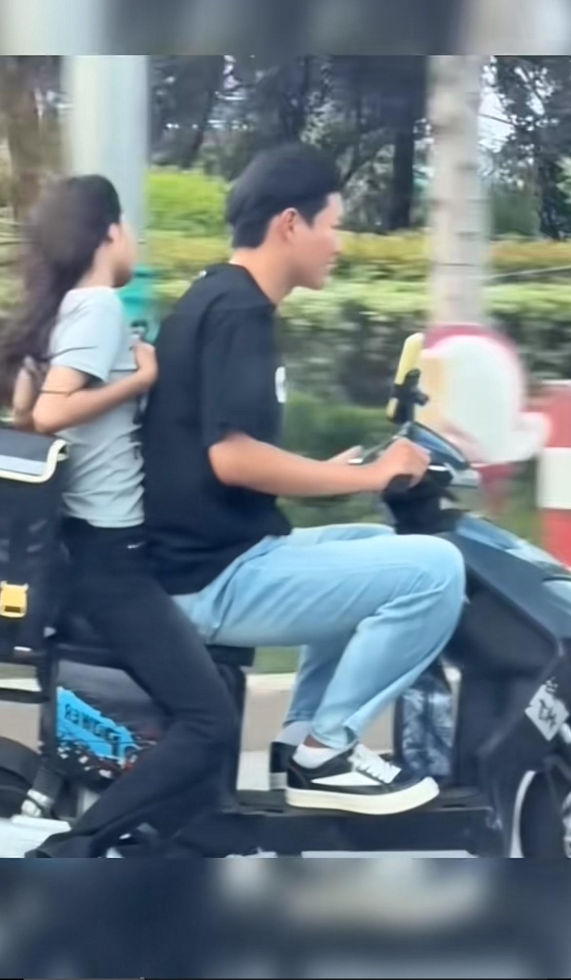 红绿灯下那对在电动车上的夫妻,画面挺让人唏嘘。女子紧紧护住胸部,这场景怪尴尬的。