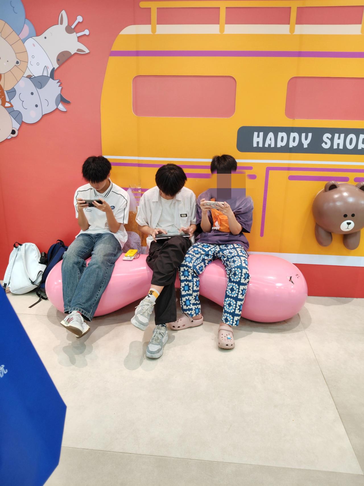 这个画面很多地方都很常见，年轻一代就毁在手机与游戏上了！现在经常看到商店门口坐