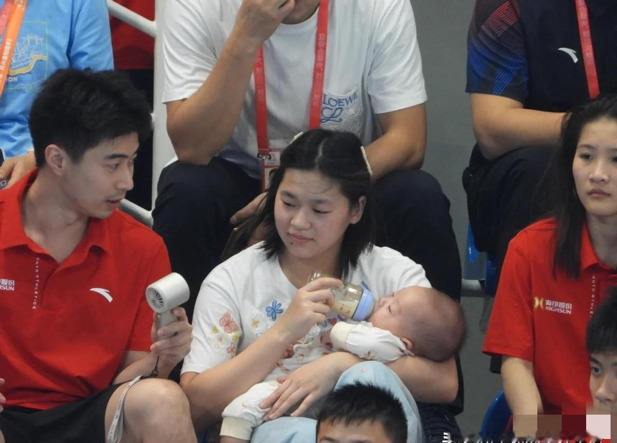 全红婵在看台喂奶，手稳得像在做空翻。谢思埸蹲边上，一句话没说，眼神却替她扛了半