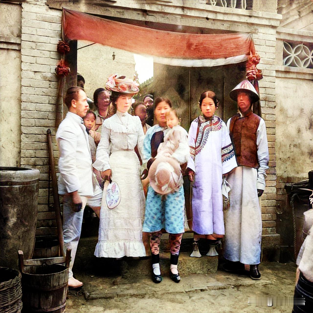 清末时期的北京，一对新婚的满族男女在门前和前来贺喜的洋人合影。新娘穿着很高的花盆