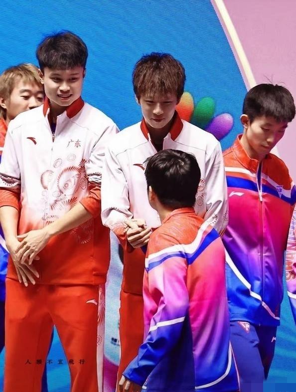 照片中的林高远眼神饱含暖意，面带微笑紧紧地握着樊振东的手，一旁的周启豪也是眼含爱