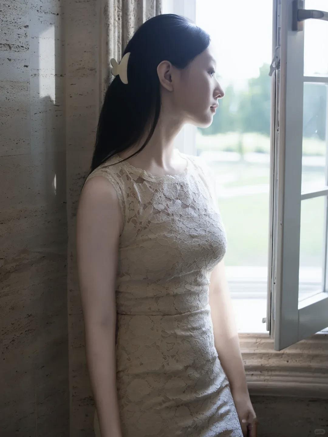 一位女生靠窗，穿着蕾丝连衣裙。