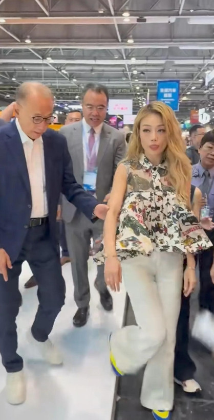 香港车展上，容祖儿风采照人，巨星范儿十足。老板杨受成紧紧相随，下坡时还拉住她手臂