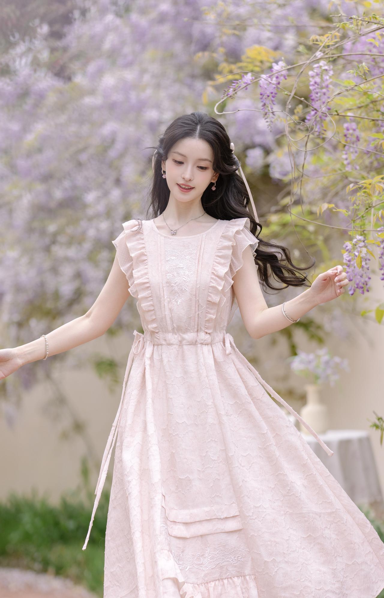 紫藤垂落，漫染一帘浅紫温柔。一袭浅粉裙裾，轻赴春日的浪漫邀约。风拂发丝，书页
