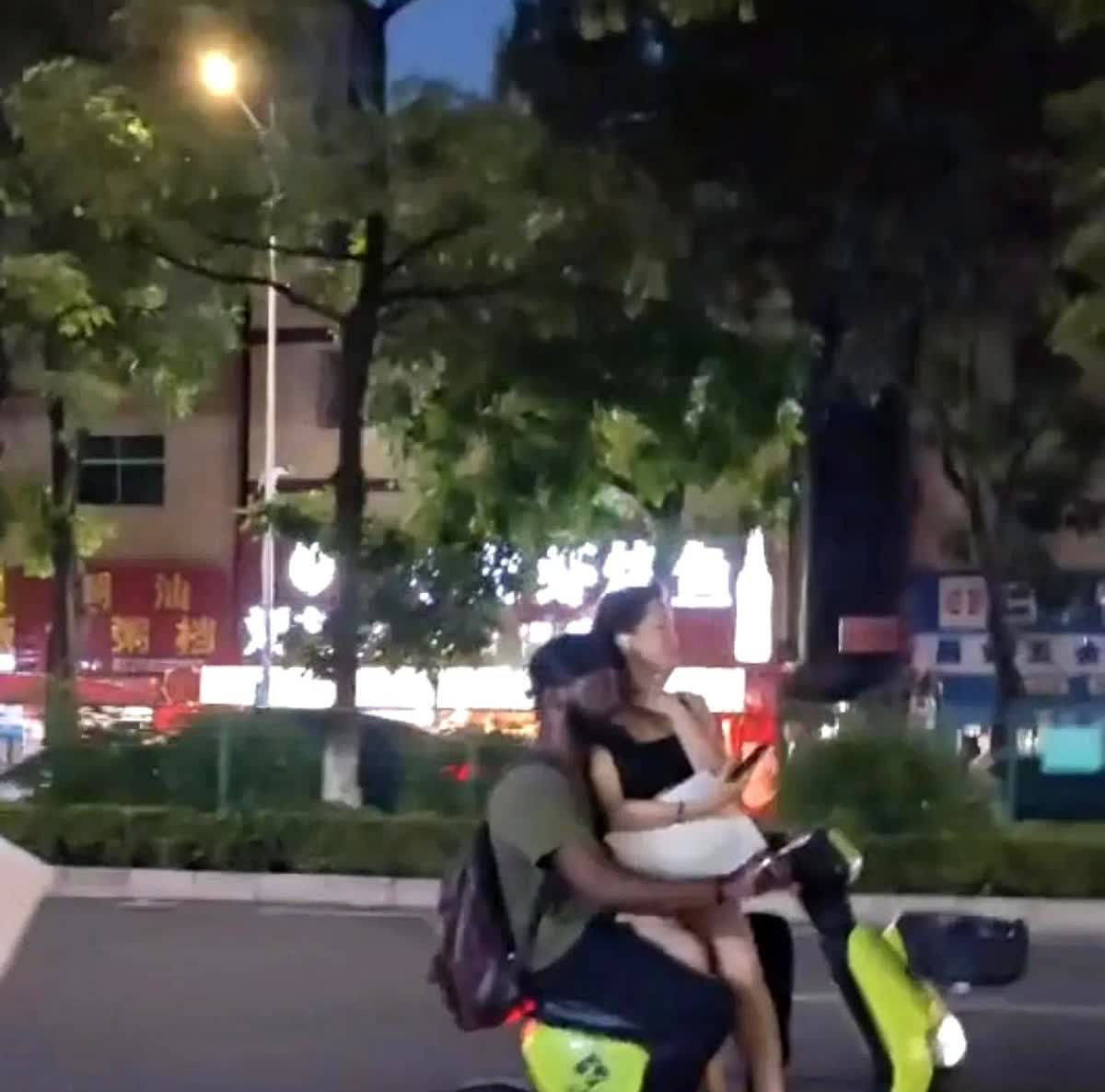 某繁华街道，一黑人男子骑电动车穿梭在街道，他路过之处路人纷纷投来惊诧目光，不是男