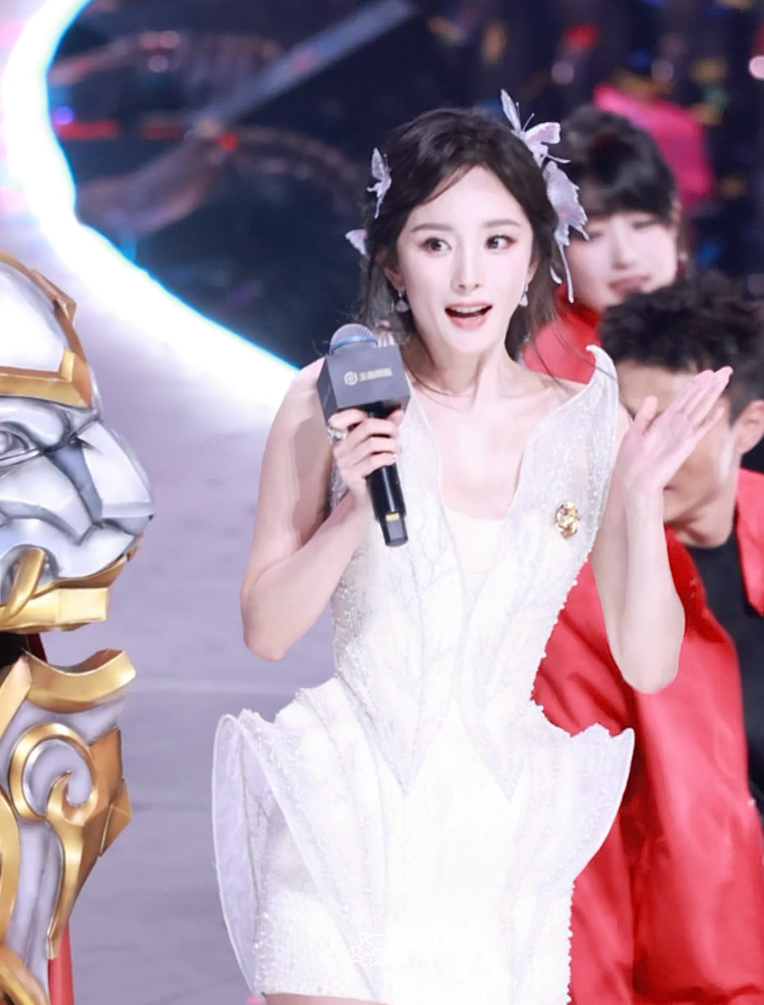 彩带的色彩斑斓与她的美丽相得益彰，她比出的爱心仿佛带着满满的爱意，透过屏幕都能感