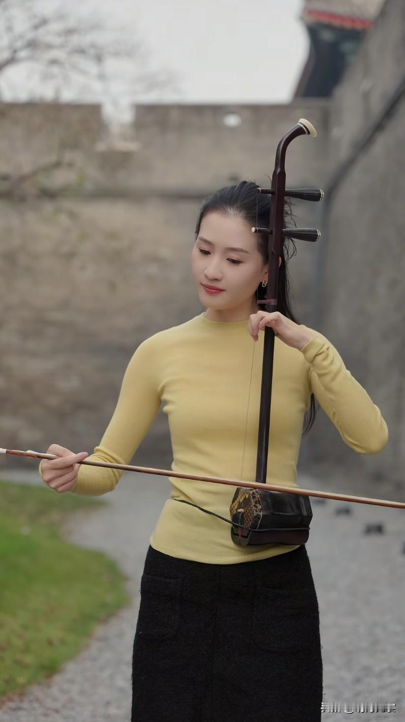 冬日墙角边，独自拉二胡的美女。投入到音乐里时，神情很迷人。二胡小美女街拍美女