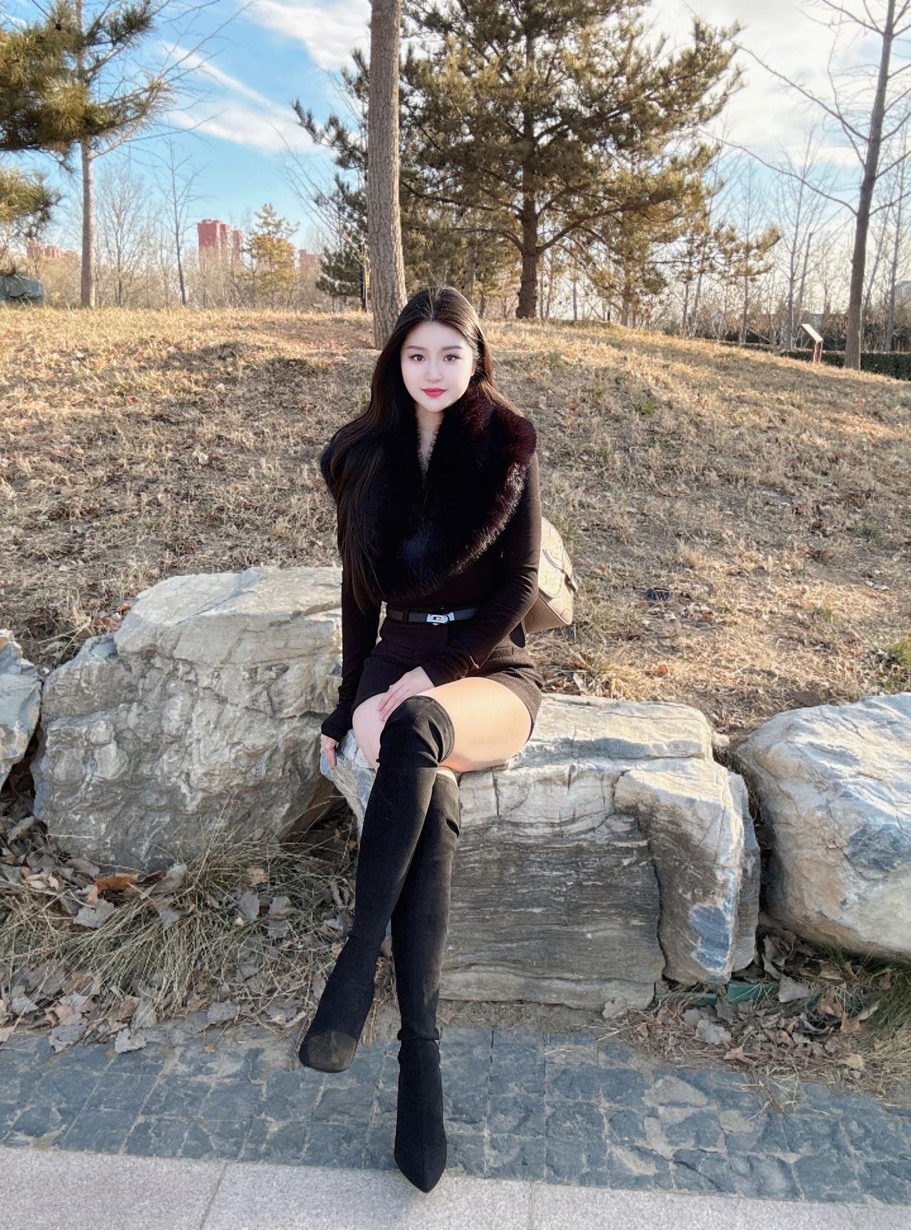 冬日暖阳下，优雅黑裙与毛绒外套的完美搭配，尽显时尚与温暖。