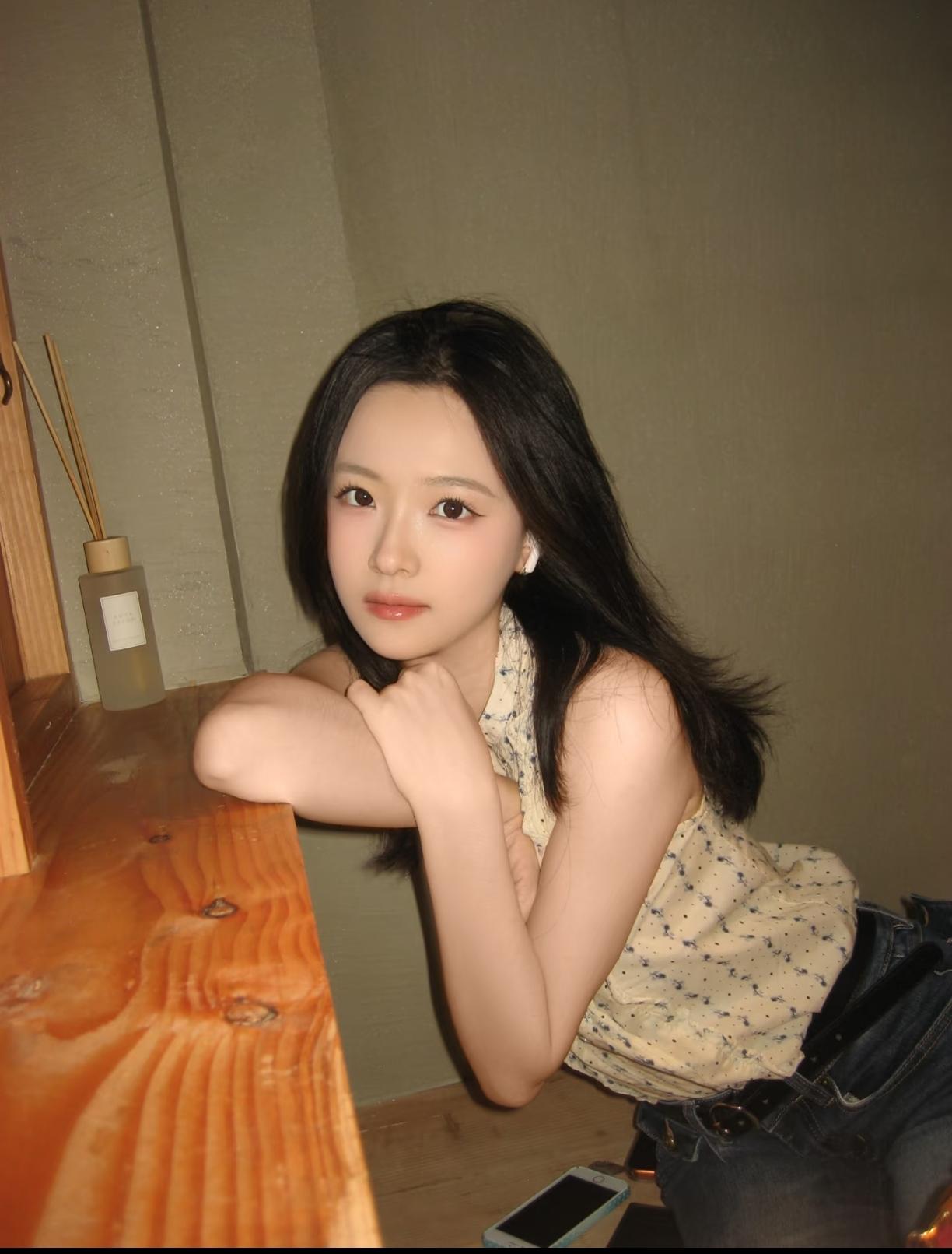 一个女孩靠在桌子上，看着镜头。