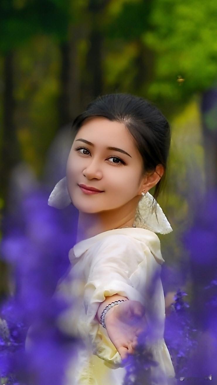 紫雾缭绕群山，春光晕染清欢。白衣女子伫立花间，回眸之际眼波盈盈流转，伸手