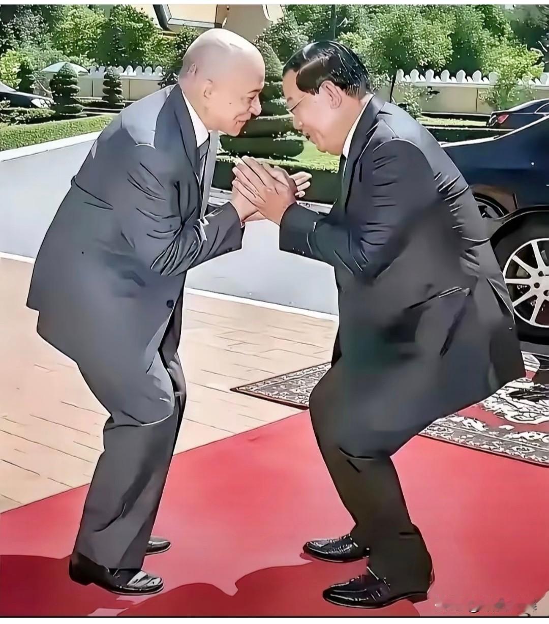 红毡铺地，绿植装模作样，西哈莫尼和洪森两人西装革履的人躬身合十——呵，这画面看着