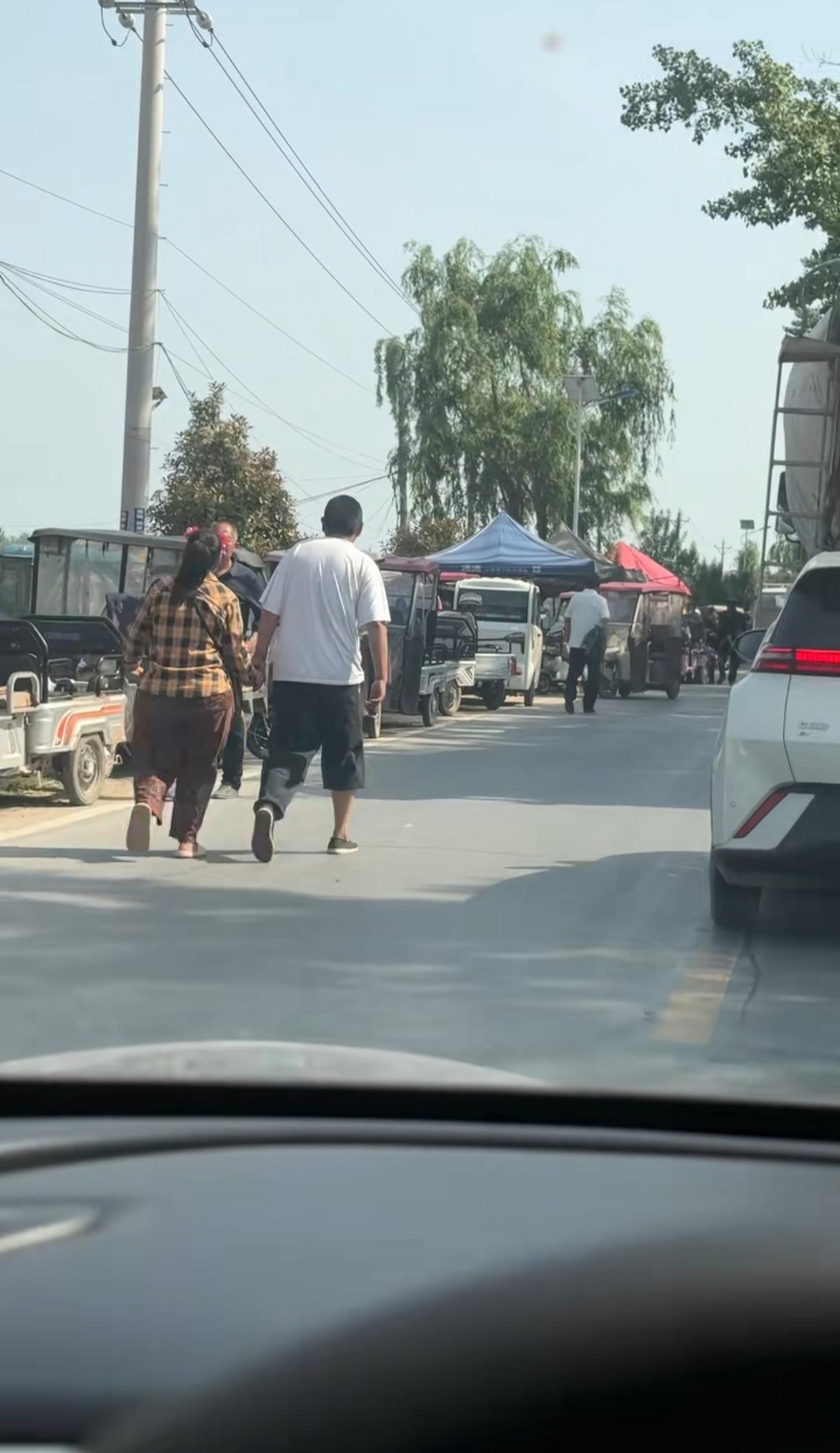 一网友在街上偶遇一对逛街的夫妻，女的膀大腰圆，夫妻俩手牵手在街上闲逛，视频发到