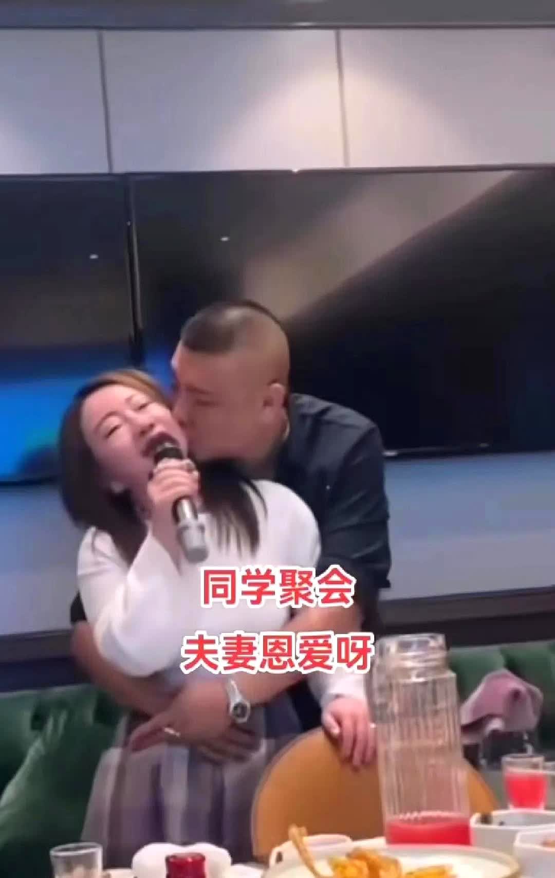 唱歌的女人被一个S迷迷的男人紧紧搂着腰，男子忽儿亲女子的脸，忽儿亲女子的耳朵，女