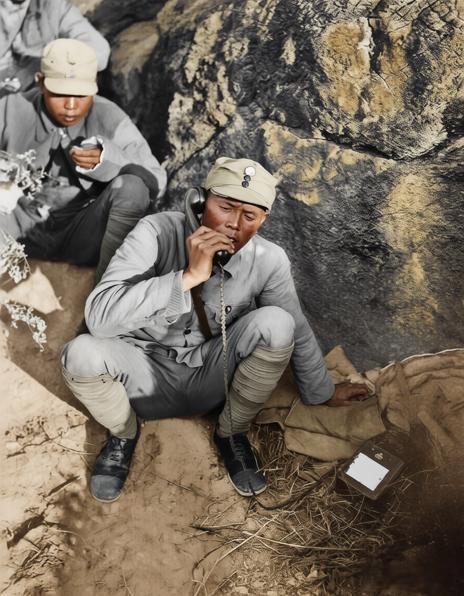 这张由著名战地摄影师沙飞于1939年拍摄的照片，一名八路军指挥员蹲在岩石掩体后，