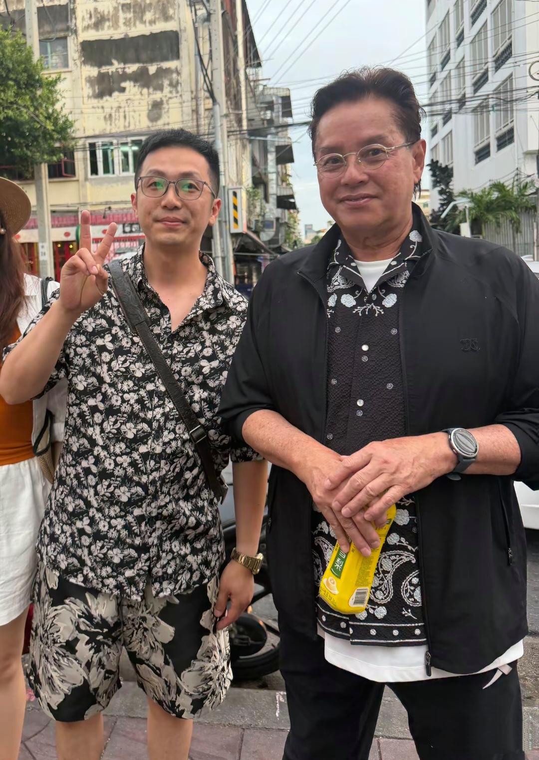 谭咏麟现身泰国街头游玩，他手里拿着一瓶冰糖雪梨，满脸都是疙瘩，这皮肤太粗糙了，胳