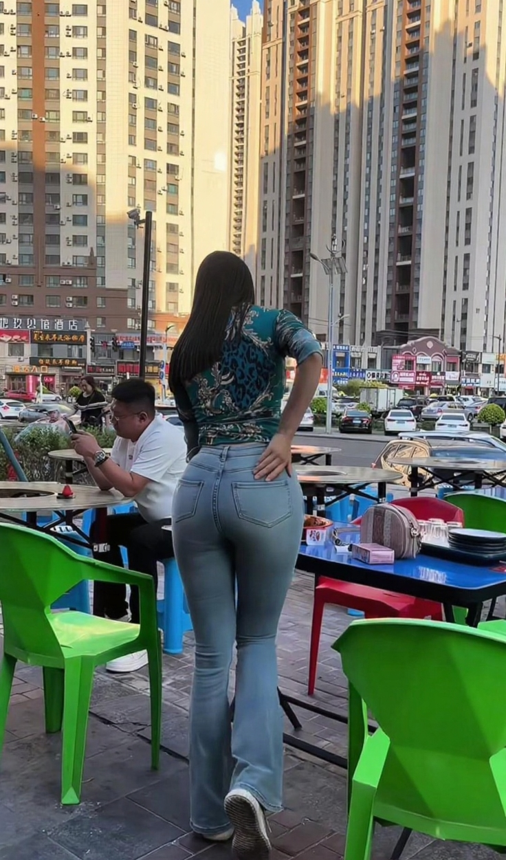 街头偶遇时尚一幕，小姐姐一身穿搭把时髦感拉满，紧身衣勾勒出随性，喇叭牛仔裤又添几分复古韵味，在城市楼