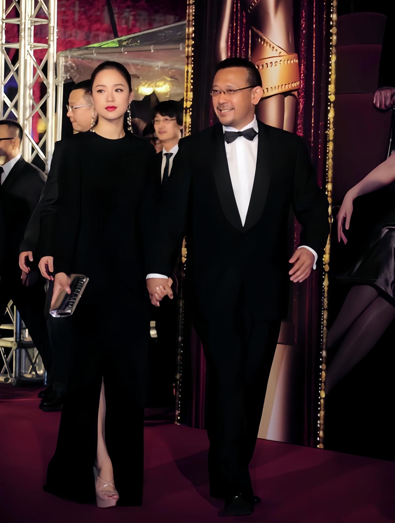姜文携老婆周韵走红毯旧照，他牵着小15岁娇妻的手，笑的好开心啊。而周韵身穿黑