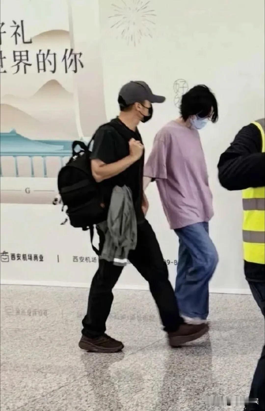 谢霆锋演唱会结束后，和王菲手牵手离开西安。王菲戴着口罩，穿着一件紫色的T恤配牛