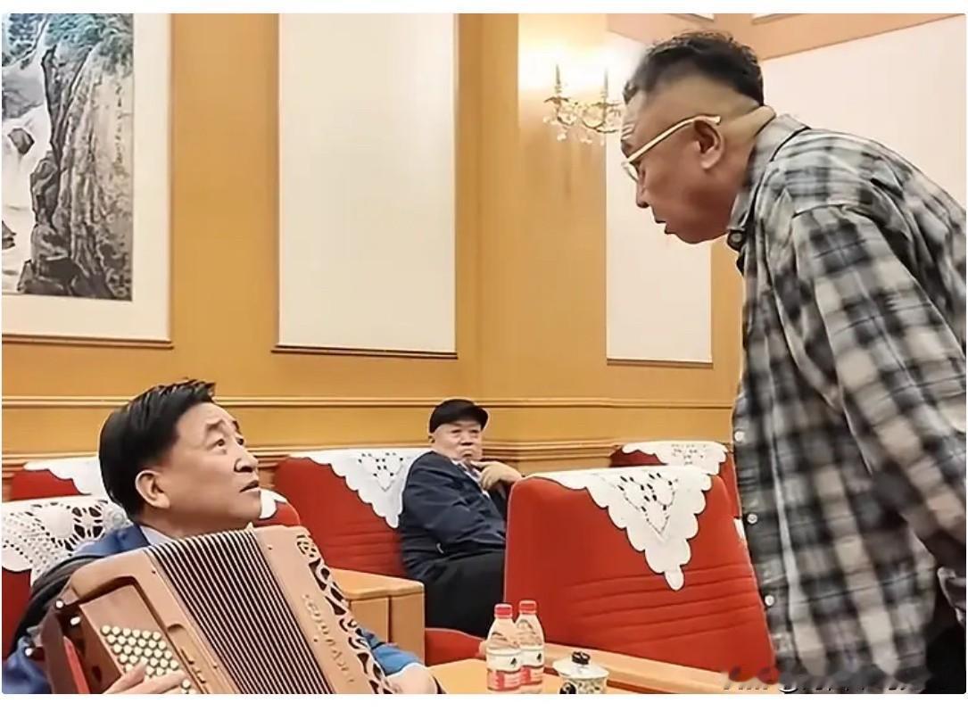于谦和姜昆见面打招呼时的张留影。起身的于谦微微俯身，姿态谦和，认真表述，姜昆端坐
