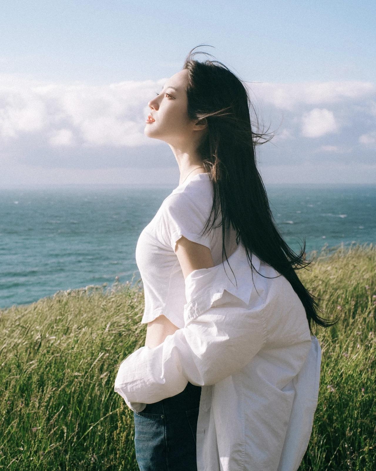 海边微风拂面，少女轻闭双眼，享受宁静时光。面朝大海，春暖花开在你眼里，什么样的女