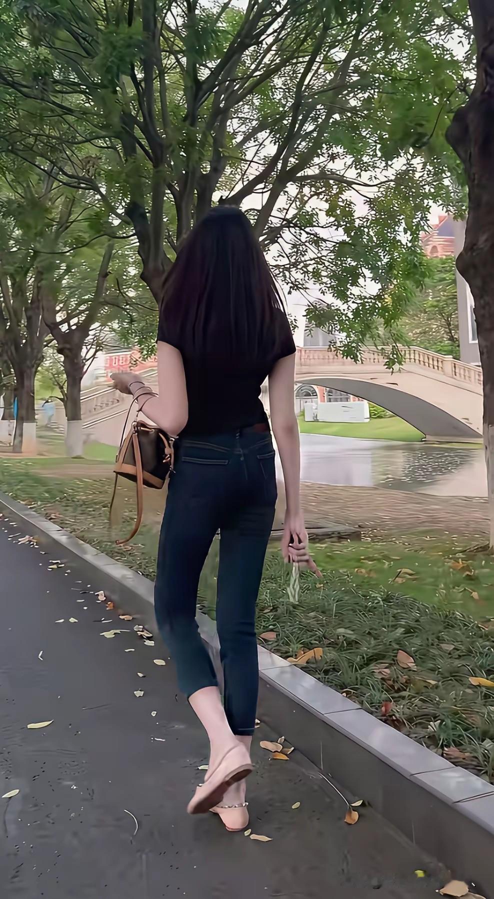 运河边上的秦淮美女，T恤牛裤，左挽包，右握手机，一枚大喑戒指颇显眼，给后面看的。