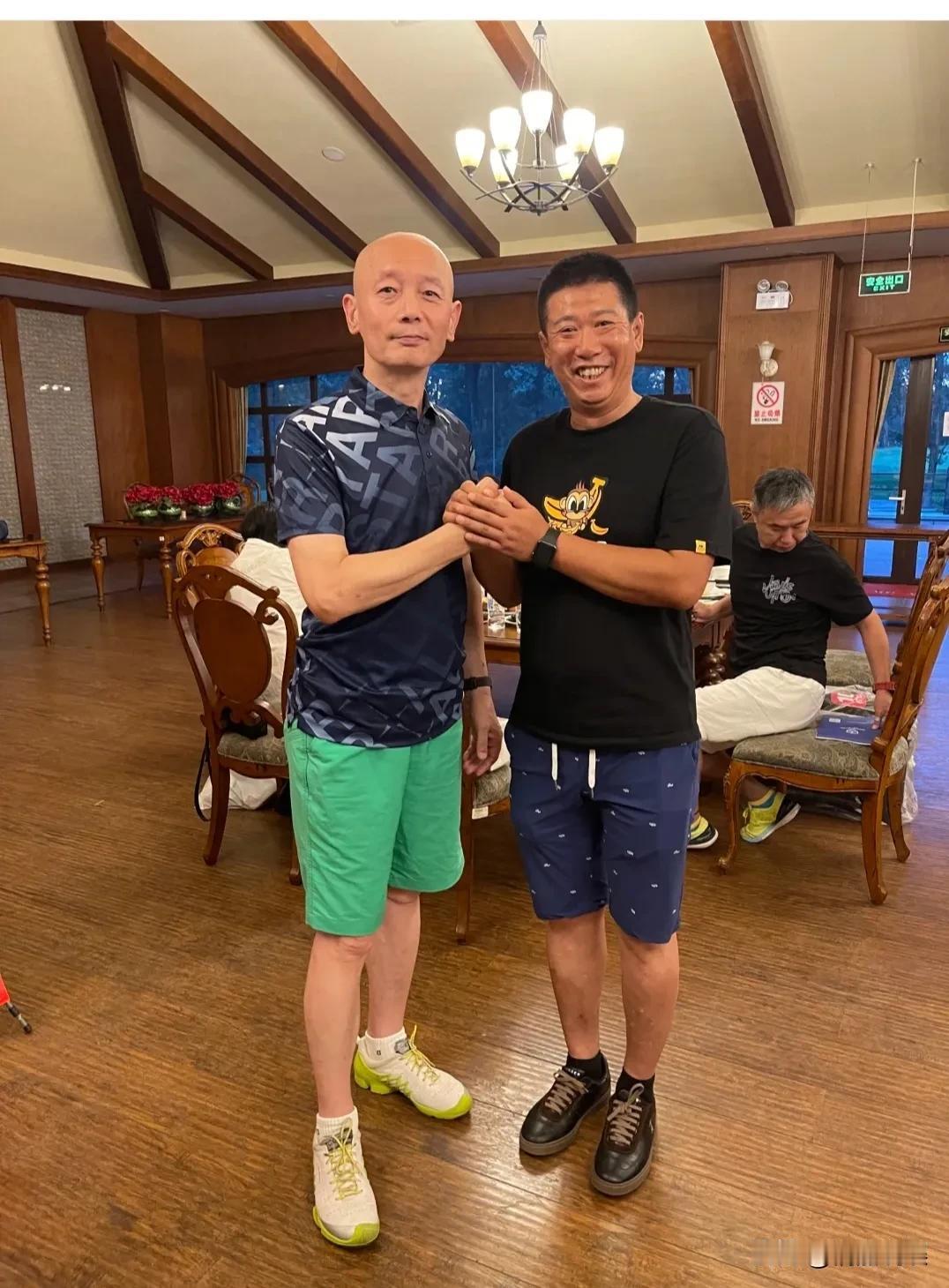 葛优和高尔夫球友合影，快七十的他，顶着标志性的光头，穿着深蓝色短袖，绿色短裤，皮
