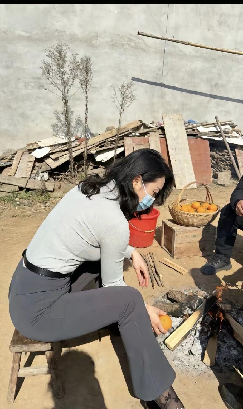 今天去邻居大伯家串门，看到一个身材超好的女人在火堆旁烤橙子！戴着口罩，穿着一套紧