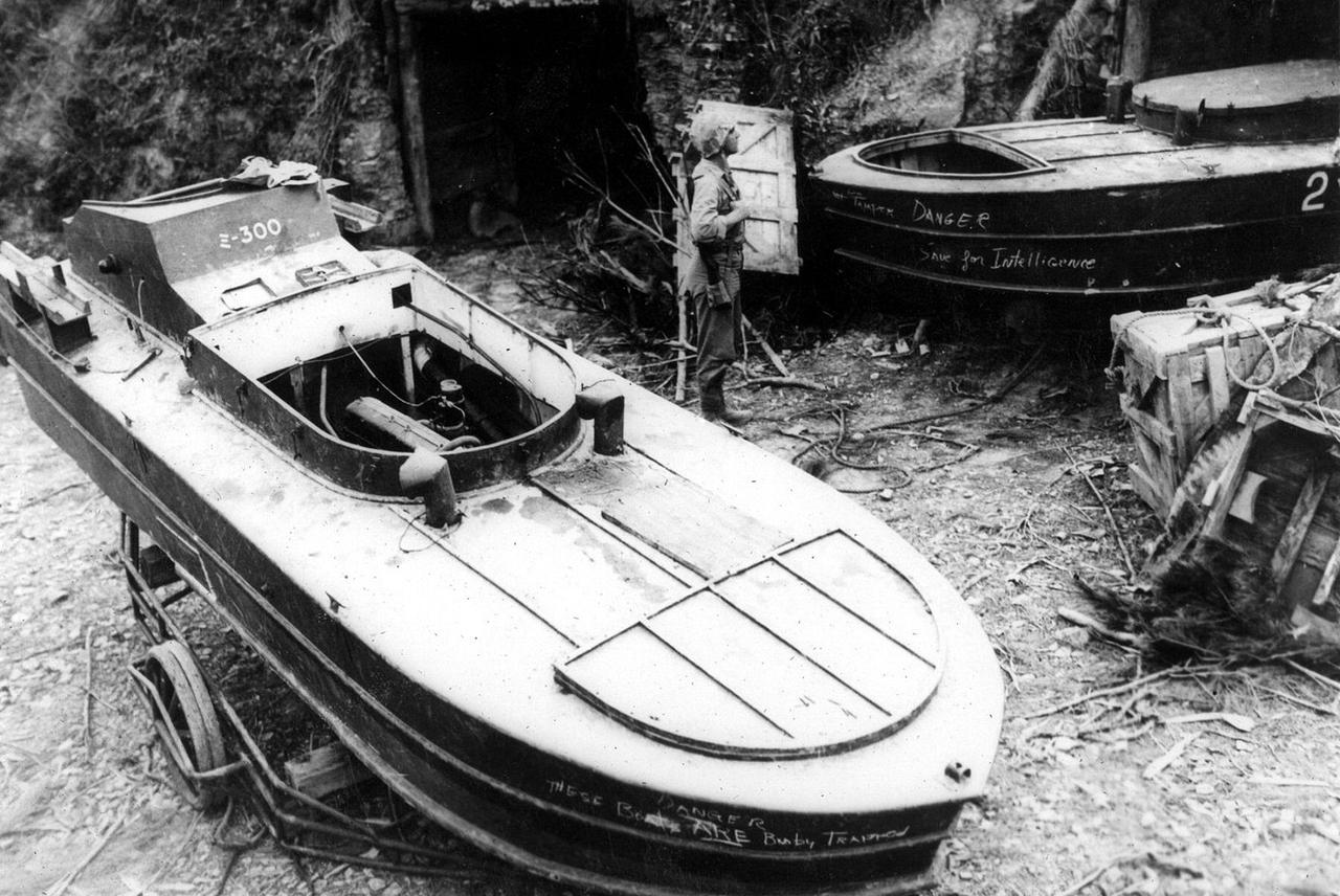 1945年，一名美军士兵在冲绳岛观看堆积如山的缴获的日军“震洋”式一号型特攻艇。