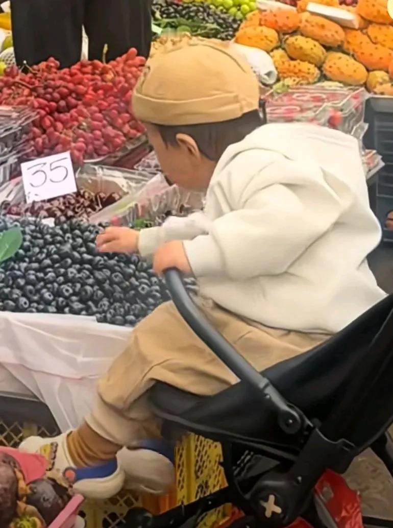 家长带着小孩来到水果摊，小孩趁家长挑水果时，直接拿起了蓝莓，吃了起来，并且这速度
